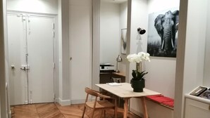 A hallway with a herringbone wooden floor, a white door, a desk with a lamp, and a framed elephant picture on the wall. - Etoile-Champs Elysée (Paris)