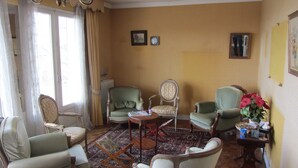 A room with a traditional layout, including a sofa, two armchairs, a small table, and a patterned rug. - Villa in the center of Crozon (Crozon)