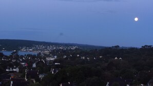 A coastal town at dusk with a visible moon. Houses are clustered along the shoreline, and a body of water is in the foreground. - Villa in the center of Crozon (Crozon)