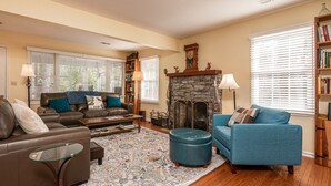 A living room with a fireplace, leather sofas, a blue armchair, and a patterned rug.