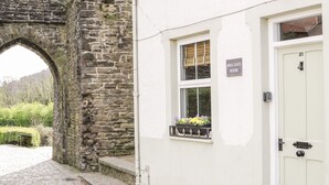 Un arco de piedra que da paso a un edificio blanco con un letrero que dice 'Mill Gate House'.