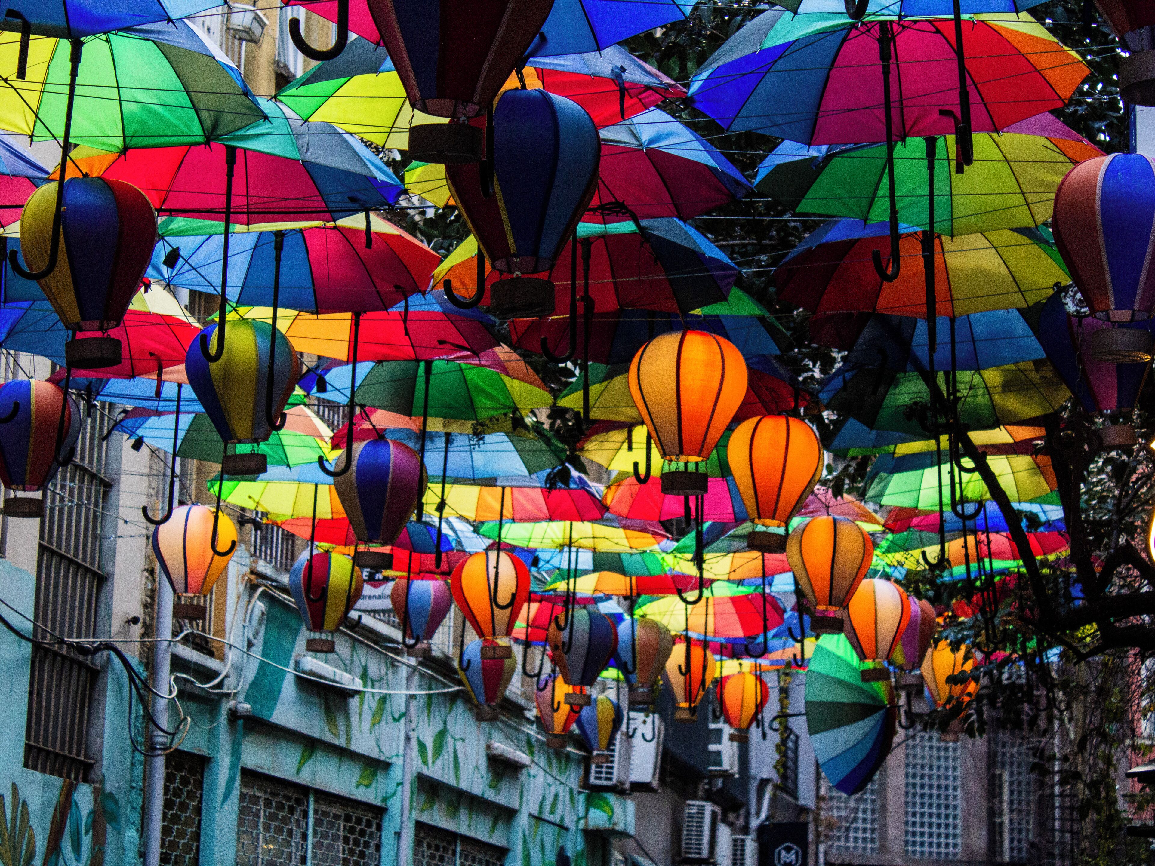 Una calle con sombrillas de colores y globos aerostáticos.