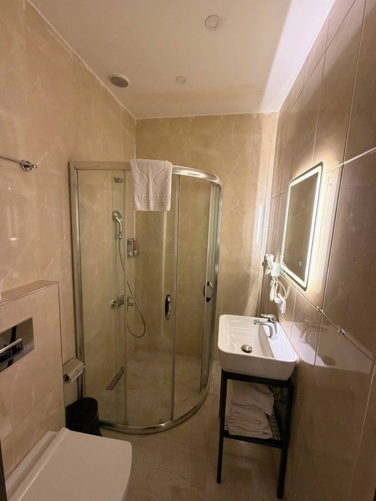 A bathroom with a glass-enclosed shower, a sink with a mirror, and a toilet.