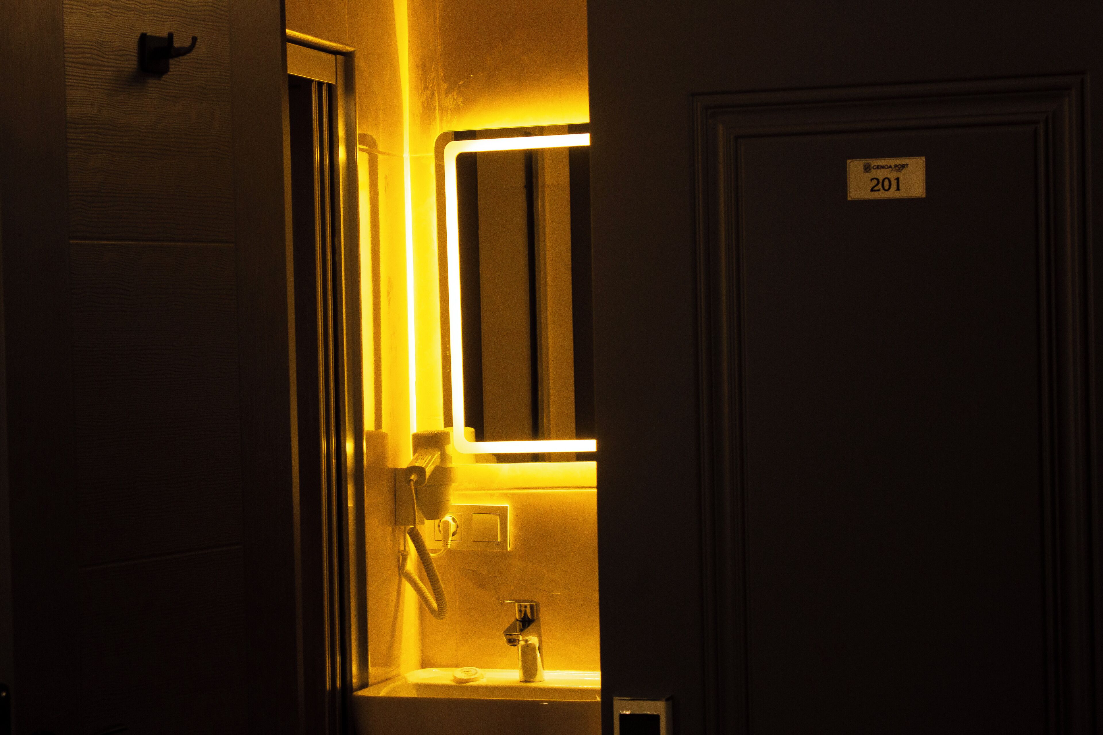 Habitación de hotel con baño que incluye un lavamanos, espejo y una puerta con la etiqueta '201'.