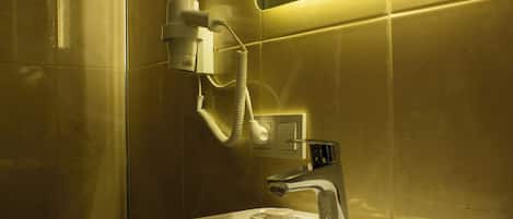 A bathroom with a white sink, a mirror, and a hairdryer mounted on the wall.