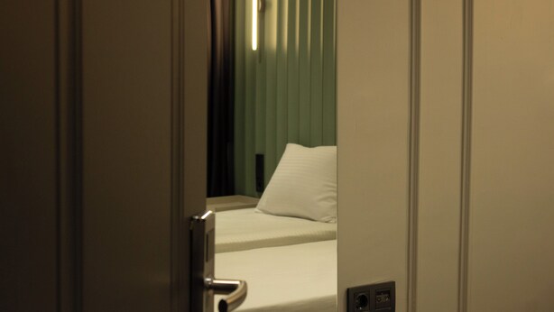 A hotel room with a bed, a door, and a wall socket. - Genoa Port Hotel (Istanbul)