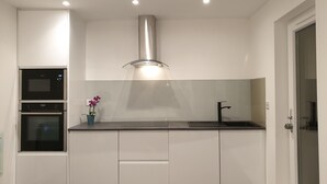 A modern kitchen with white cabinets, a stainless steel range hood, a built-in oven, and a black faucet. - Stylish detached studio with a wet room, Satellite TV & other amenities 😀 (Bristol)