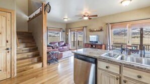 A spacious kitchen with a dishwasher, wooden cabinets, and a large window offering a mountain view. - Cozy Home-Spectacular Mountain Views / ATVs Welcome (Creede)