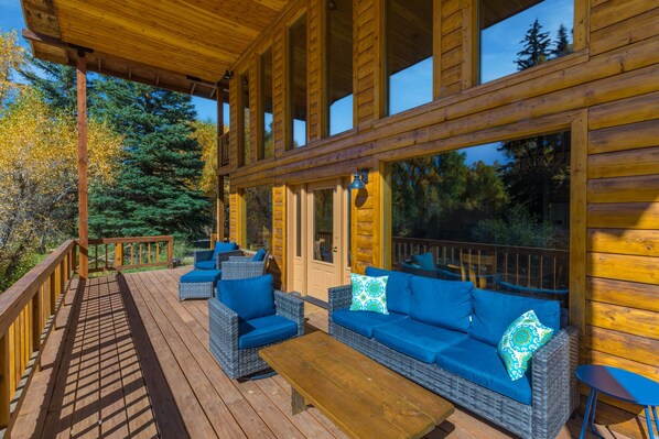 A wooden deck with wicker furniture and a wooden table.