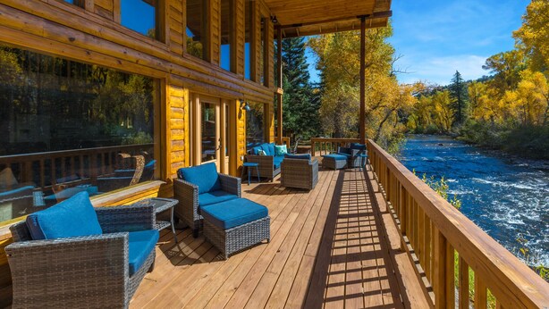 Eine Holzterrasse mit Korbmöbeln und Blick auf einen Fluss.