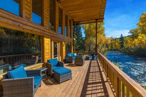 A wooden deck with wicker furniture and a view of a river.