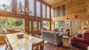 Ein Interieur einer Holzhütte mit Essbereich, einer Couch und einem roten Sitzsofa.