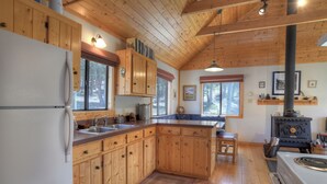 A cabin-style kitchen with wooden cabinets, a refrigerator, a sink, and a stove. - Secluded Mountain Cabin - Pet Friendly - National Forest Access (Creede)