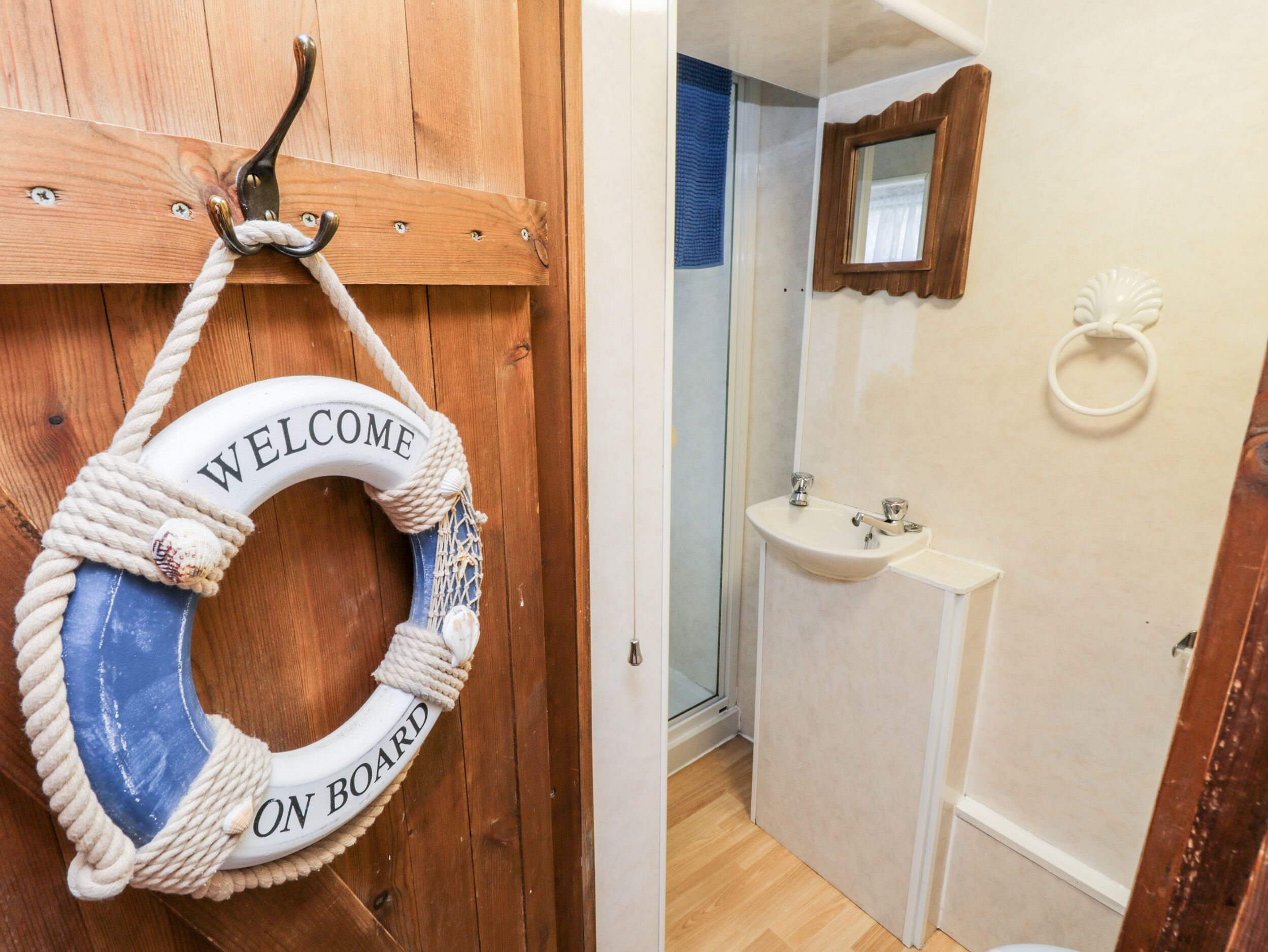 A wooden door with a welcome sign and a life ring, and a bathroom with a sink and mirror.
