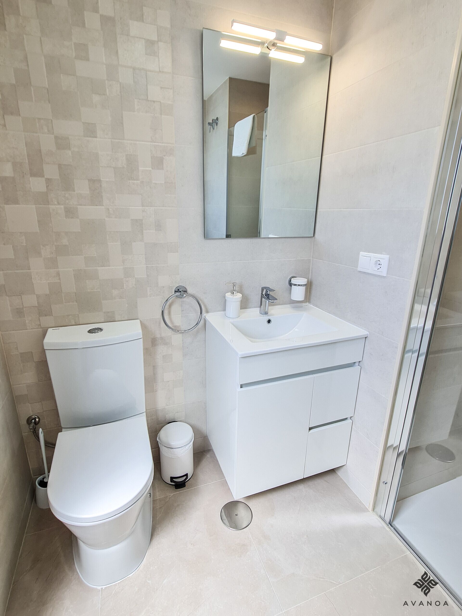 A modern bathroom with a toilet, sink, and mirror.