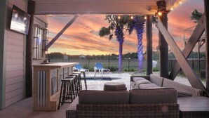 A covered outdoor seating area with a bar, lounge chairs, and a view of the sunset. - Short walk to the Beach 5 BR Beach House with a Private Pool! Marsh Mellow (Murrells Inlet)