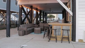 An outdoor seating area with wicker furniture, a bar, and string lights. - Short walk to the Beach 5 BR Beach House with a Private Pool! Marsh Mellow (Murrells Inlet)