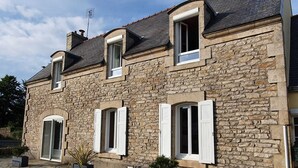 A stone building with multiple windows and shutters, featuring a stone facade and a tiled roof. - Maison typique pour 10 personnes, jardin clos et fleuri, proche plage (Treffiagat)