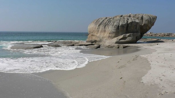 A beach with a large rock formation, calm sea, and clear sky. - Maison typique pour 10 personnes, jardin clos et fleuri, proche plage (Treffiagat)