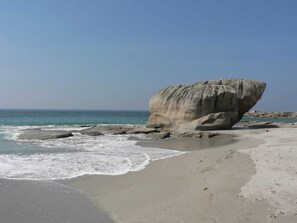 A beach with a large rock formation, calm sea, and clear sky. - Maison typique pour 10 personnes, jardin clos et fleuri, proche plage (Treffiagat)