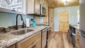 A kitchen with wooden cabinets, granite countertops, a stainless steel sink, and a built-in oven. - It`s all new at Village Sunset, sweet little hidea (Blowing Rock)
