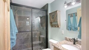 A bathroom with a glass-enclosed shower, a white toilet, and a granite countertop sink. - It`s all new at Village Sunset, sweet little hidea (Blowing Rock)