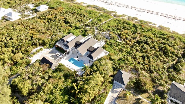 An aerial view of a coastal property with a swimming pool, surrounded by dense vegetation and a beach in the background. - Private Villa Directly on Windermere Beach, Private Pool, Tennis (Savannah Sound)