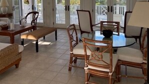 A spacious room with a high ceiling, a ceiling fan, a round window, and a view of the ocean through large glass doors. - Private Villa Directly on Windermere Beach, Private Pool, Tennis (Savannah Sound)