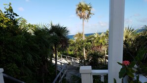 A wooden staircase leading to a white porch surrounded by lush greenery and a palm tree. - Private Villa Directly on Windermere Beach, Private Pool, Tennis (Savannah Sound)