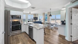 Una cocina moderna con electrodomésticos integrados, una isla grande y vistas a la playa.