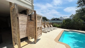 Ein Poolbereich mit Holzterrasse, Liegestühlen und einem Schwimmbecken.