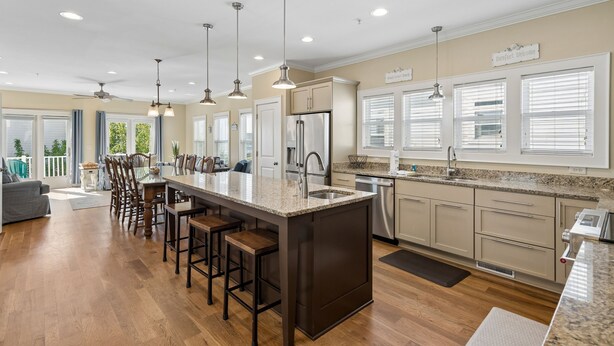A spacious kitchen with a central island, bar stools, pendant lighting, and a view of the outdoors. - Pool, ocean views from rooftop deck, one street from the beach and shops! (Isle of Palms)
