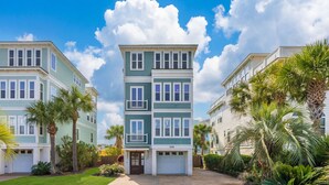 A multi-story residential building with a central entrance, surrounded by lush greenery and palm trees. - Pool, ocean views from rooftop deck, one street from the beach and shops! (Isle of Palms)
