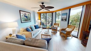 A spacious living room with a sofa, armchairs, a coffee table, and a balcony with outdoor furniture. - Shipwatch A105: Oceanfront, private balcony & spectacular views in Wild Dunes (Isle of Palms)