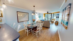 A dining area with a wooden table and chairs, a chandelier, and a framed map on the wall. - Shipwatch A105: Oceanfront, private balcony & spectacular views in Wild Dunes (Isle of Palms)