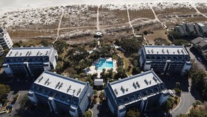 A modern hotel complex with a central swimming pool, surrounded by lush greenery and a sandy beach. - Shipwatch A105: Oceanfront, private balcony & spectacular views in Wild Dunes (Isle of Palms)