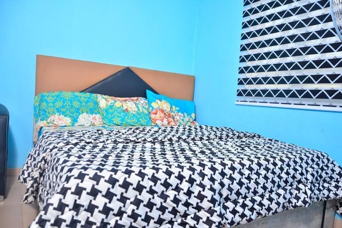 Una cama con una colcha estampada, un cabecero y dos almohadas con diseños florales.