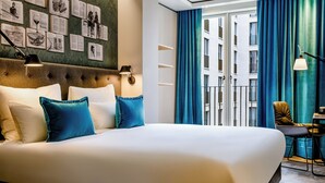 Une chambre d’hôtel avec un grand lit, une tête de lit décorée, un bureau avec une chaise et une vue sur un immeuble à travers une fenêtre ornée de rideaux bleus.
