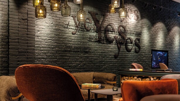 A cozy lounge area with a brick wall, leather sofas, and a small table with a book titled 'Ulysses James Joyce'. - Motel One Dublin (Dublin)