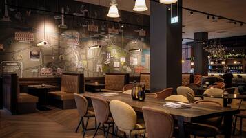 Un restaurante con un mural con temática de mapa, mesas de madera y asientos de cuero.
