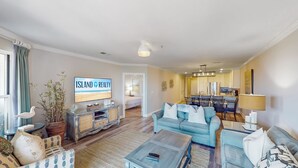 A spacious living room with a large TV, a dining area, and a kitchen. - Located in the heart of Isle of Palms with direct access to the oceanfront (Isle of Palms)