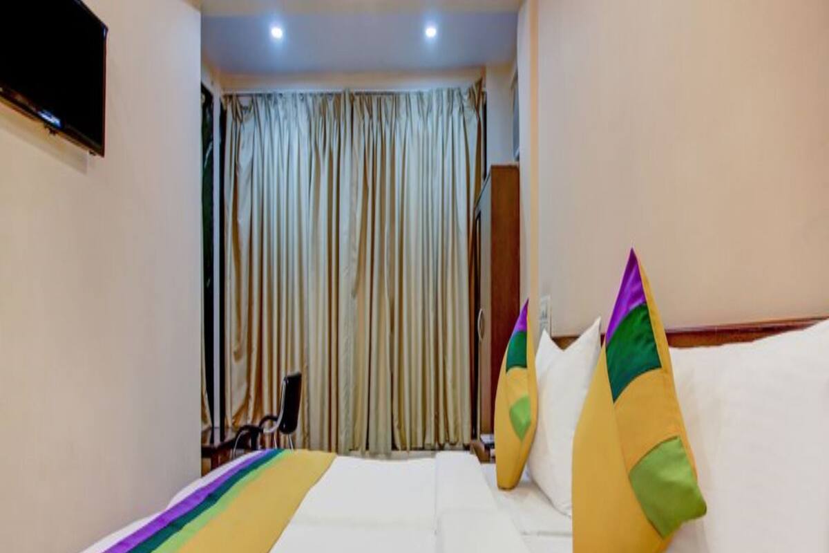 Une chambre d’hôtel avec un lit, des rideaux, une télévision et une chaise.