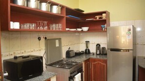 Een kleine keuken met een magnetron, kookplaat, broodrooster en koelkast.