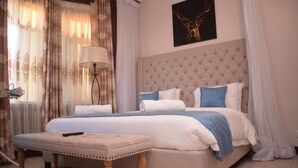 Een slaapkamer met een groot bed, een nachtkastje, een lamp en een kunstwerk aan de muur.