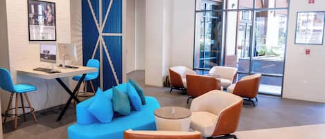 A modern lobby with a seating area, a computer desk, and a large window.