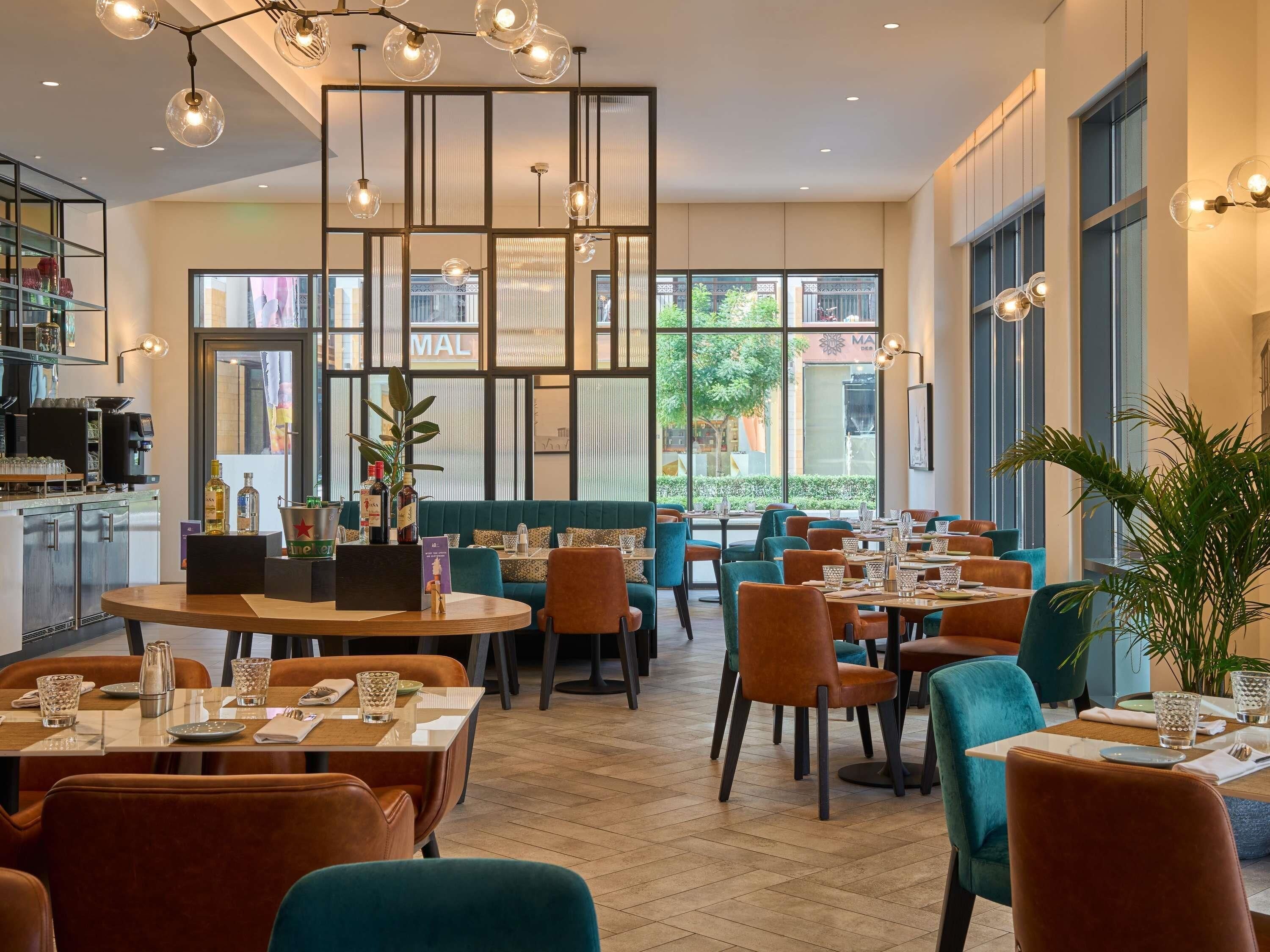 A modern restaurant with a mix of seating options, including tables and booths, and a bar area visible in the background.
