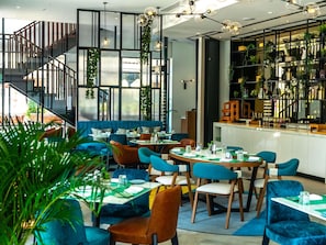 Ein modernes Restaurant mit verschiedenen Sitzgelegenheiten, darunter Tische und Boxen, sowie einer Treppe zu einer oberen Ebene.