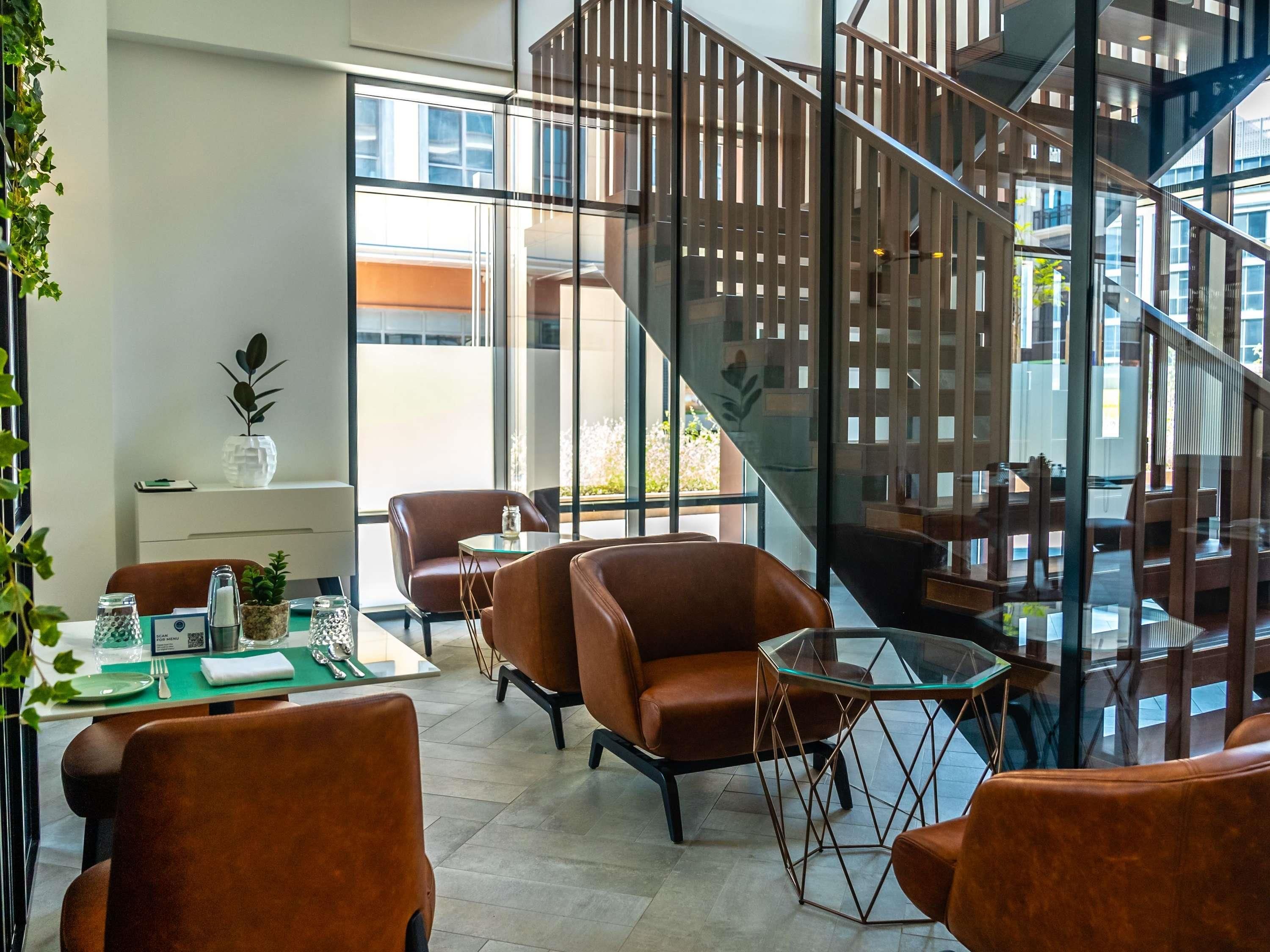 A modern interior with a glass staircase, leather seating, and a dining area with a green tablecloth.