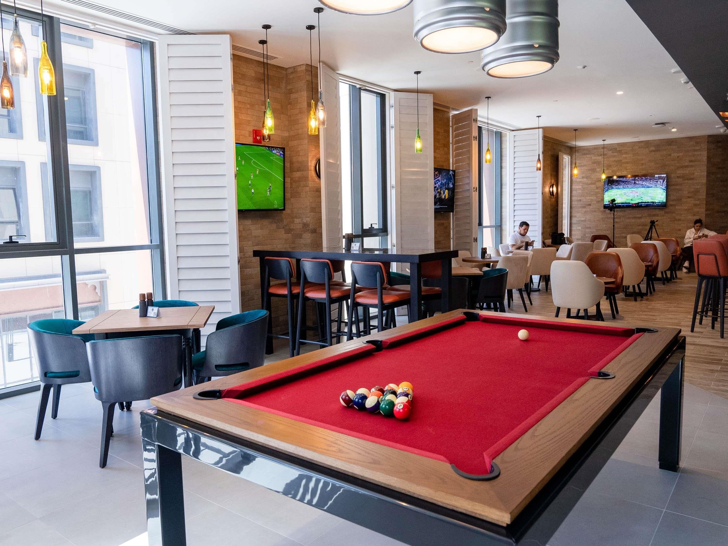 A pool table with balls, a television, and seating areas in a well-lit indoor space.