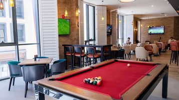 A pool table with balls, a television, and seating areas in a well-lit indoor space.